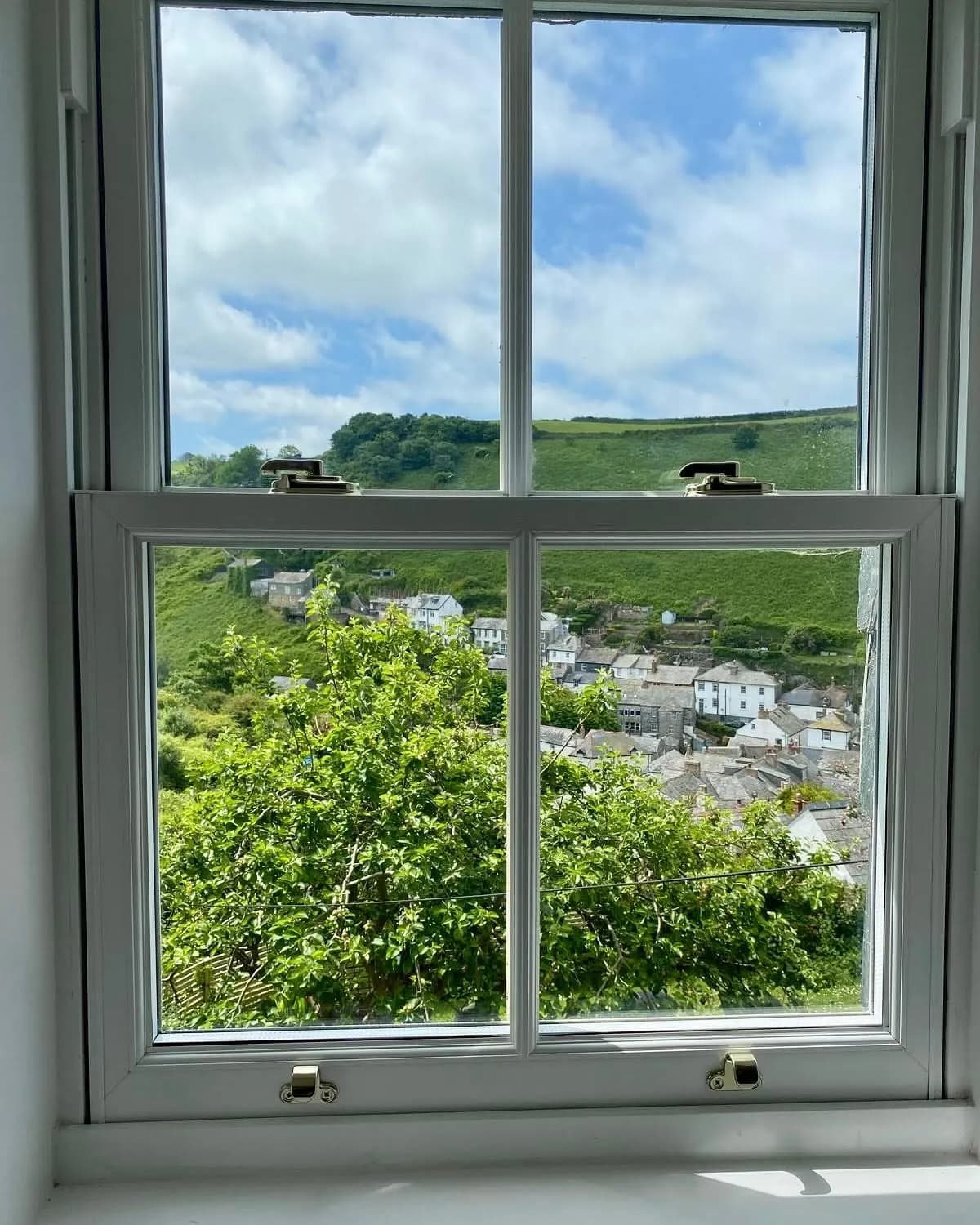 A repaired window looking out over a green Cornish valley
